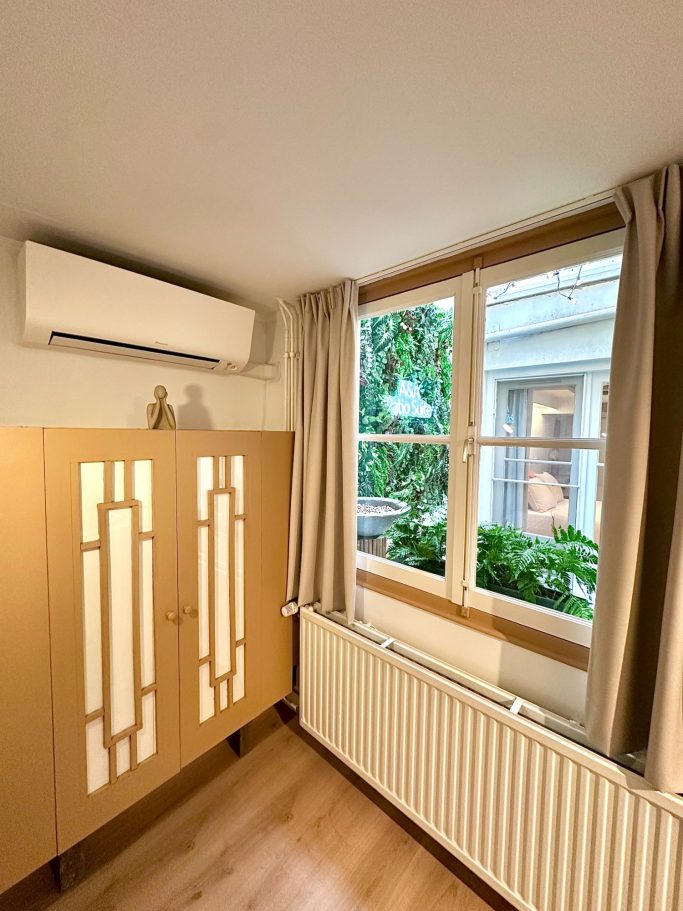 Cozy Twin Room A&A PAtio suite twin room. Een lichte kamer met een kast, raam en planten buiten.