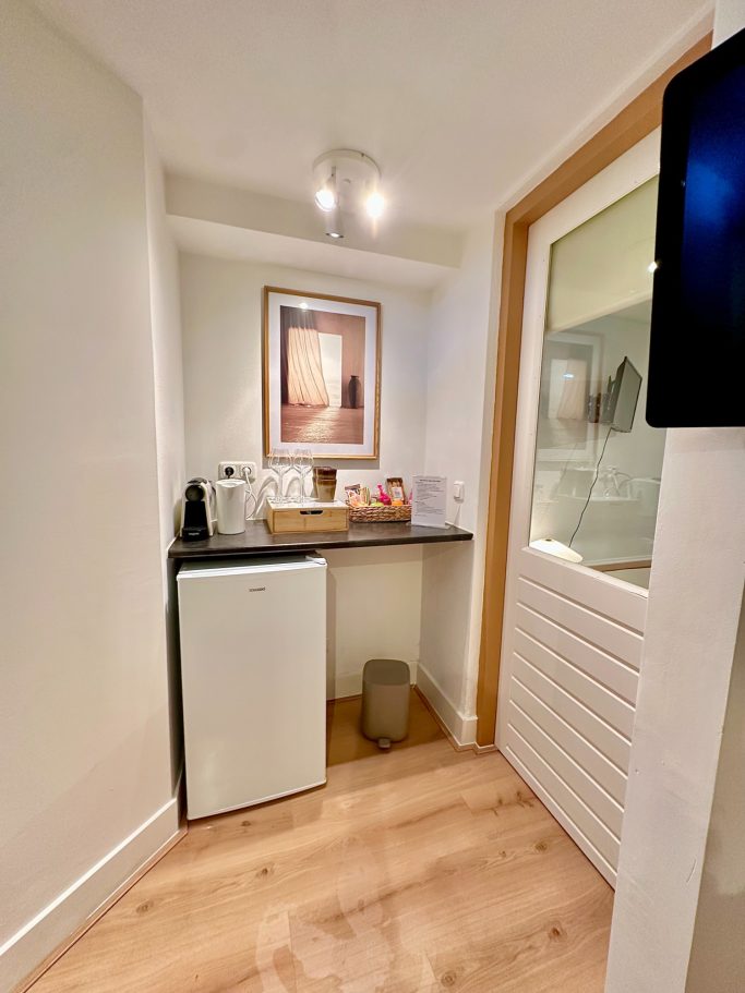 Complimentary Refreshments Area A&A PAtio suite queen room minibar.Klein keukentje met koelkast, gootsteen en een schilderij aan de muur.