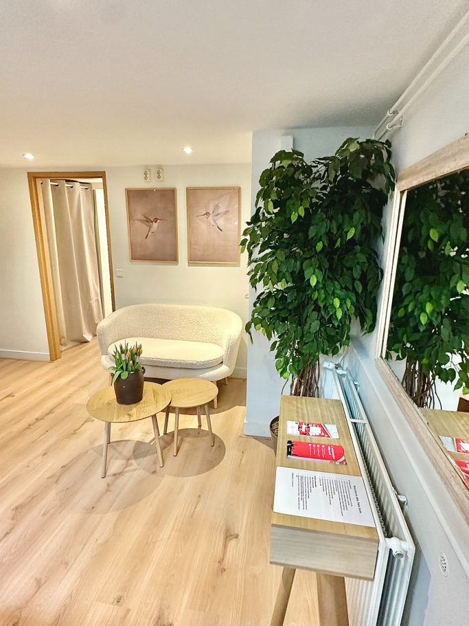 Shared Receiving Area A&A Patio Suite shared reception area- Lichte en moderne ruimte met een bank, tafeltje, planten en witte muren.