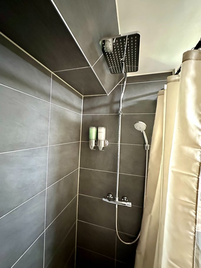 Bathroom 1 with smart toilet A&A Patio suite queen room toilet. Moderne douche met tegelwand, douchkop en zeepdispensers.