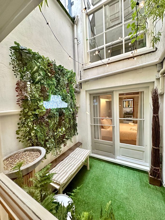 Private Patio Garden A&A PAtio suite patio garden. Kleine binnenplaats met groenwand, bankje en glazen deuren naar een kamer.